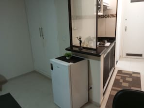 A compact kitchen with a refrigerator, a small countertop, and a potted plant.