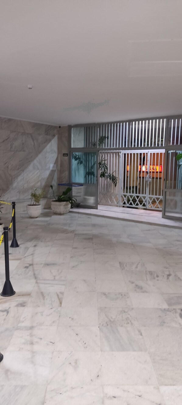 Un hall d’entrée spacieux avec un sol en marbre, un escalier et une entrée sécurisée par un portail.