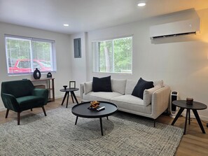 A living room with a sofa, a green armchair, a coffee table, and a small side table.