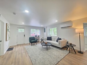 A modern living room with a sofa, armchairs, a coffee table, and a floor lamp. - The Haven at Idlewild (Idlewild)