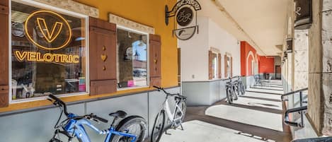 A bicycle parked outside a building with a neon sign reading 'VELOTRIC'.