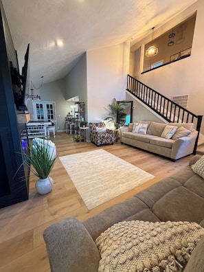 Un salon spacieux comprenant un canapé, une table basse et un escalier menant à l’étage supérieur.