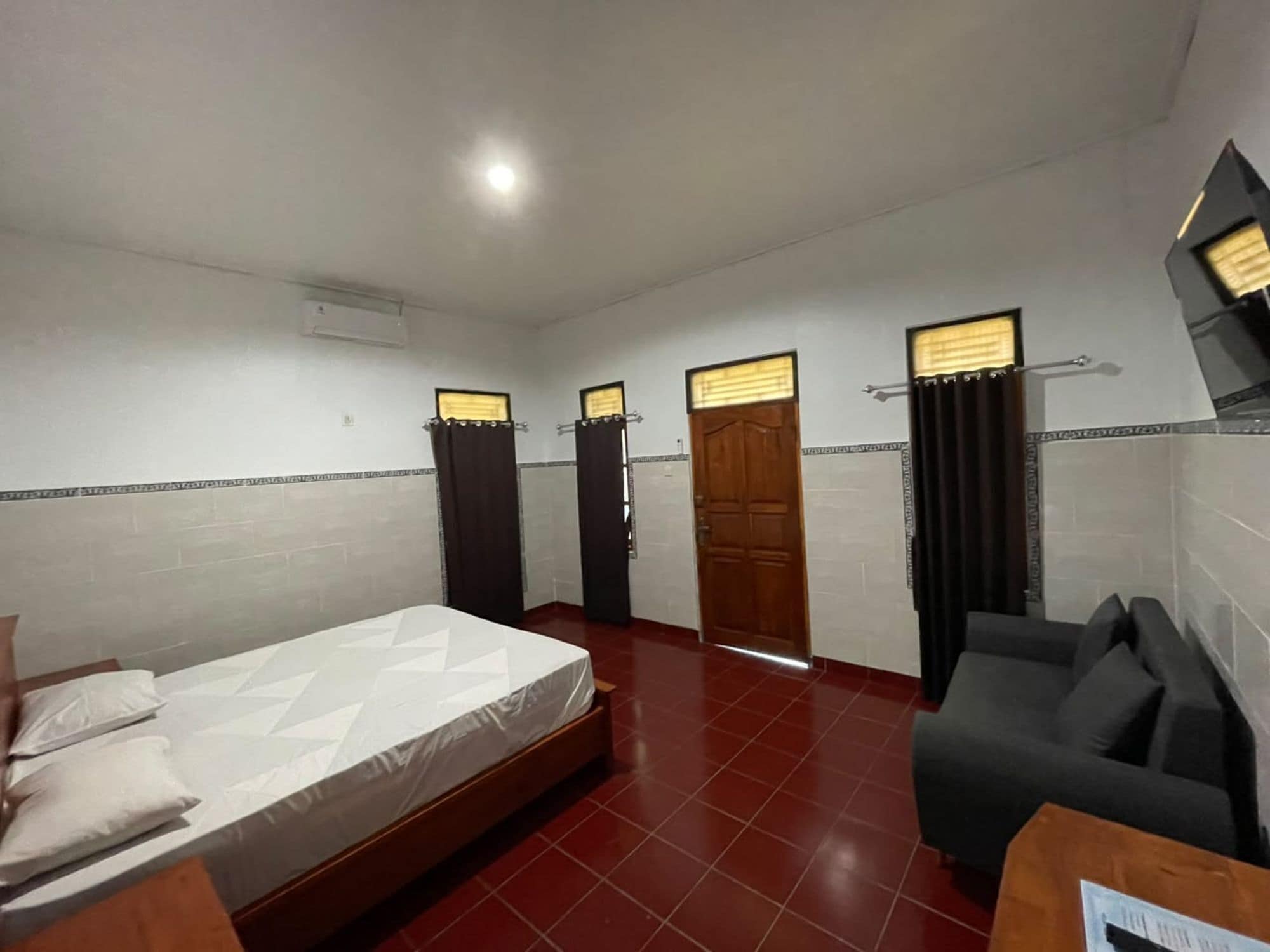 A hotel room with a bed, a sofa, a desk, and a bathroom with a shower and toilet.