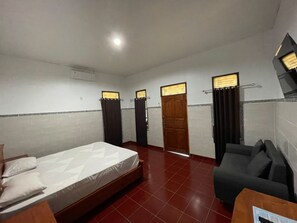 Habitación de hotel con cama, sofá, escritorio y baño con ducha e inodoro.