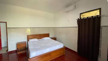A bedroom with a wooden bed, a nightstand, a mirror, and a window with curtains.