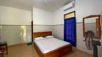 A bedroom with a wooden bed, a ceiling fan, a mirror, and a window with blue curtains.