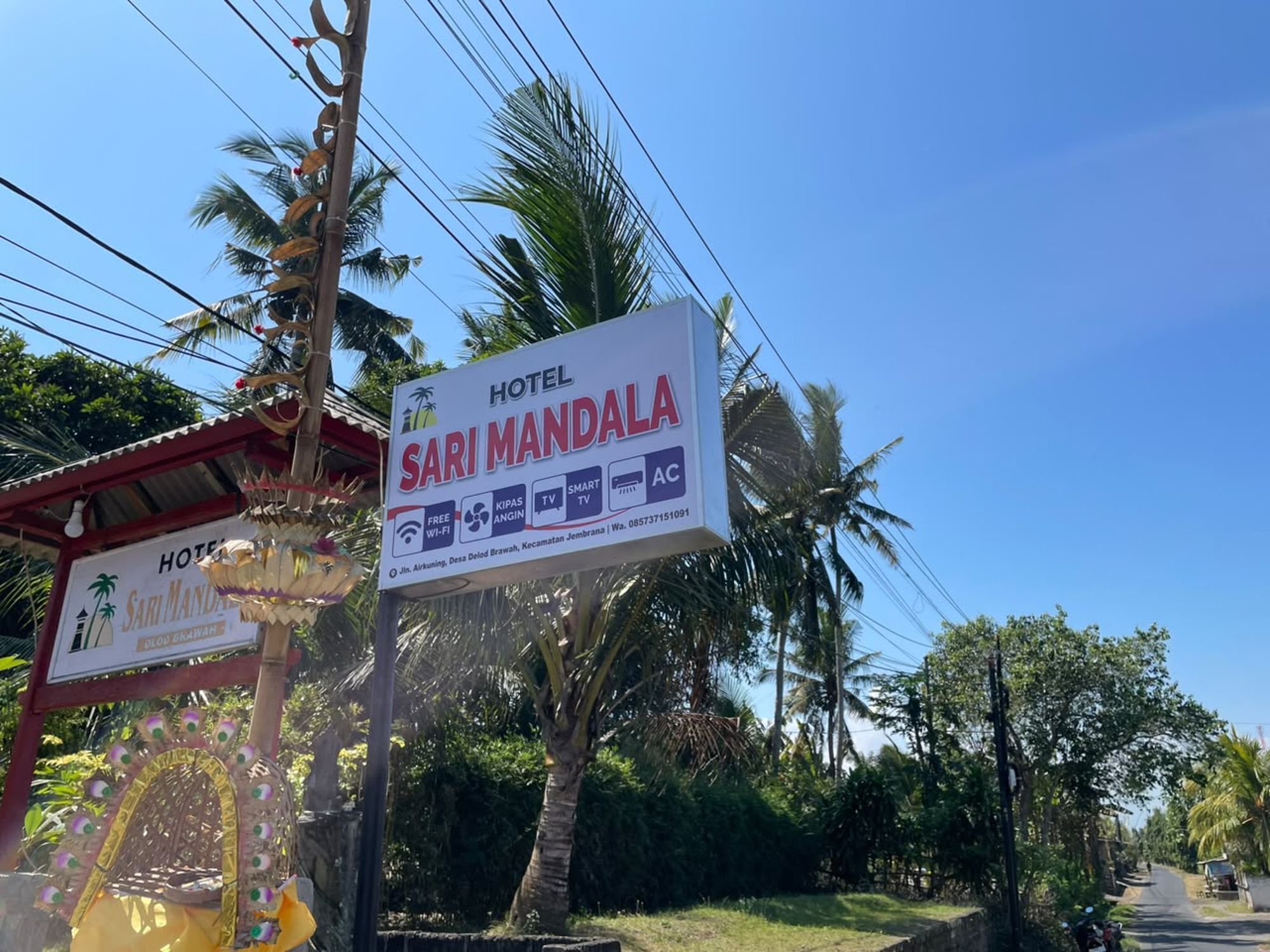 A sign for Hotel Sari Mandala with amenities like free Wi-Fi, TV, and AC.