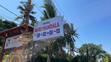 A sign for Hotel Sari Mandala with amenities like free Wi-Fi, TV, and AC.