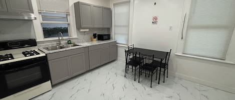 A modern kitchen with a gas stove, a microwave, and a dining table with chairs.