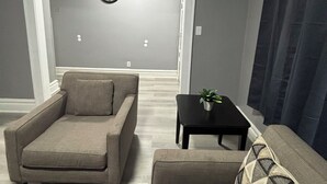 A living room with a sofa, armchair, and a small table with a plant. - Modern 2-bedroom apartment near Airport (Newark)
