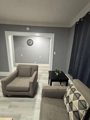 A living room with a sofa, armchair, and a small table with a plant.