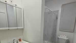 A bathroom with a white sink, mirror, toilet, and shower. - Modern 2-bedroom apartment near Airport (Newark)
