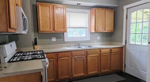 A kitchen with wooden cabinets, a double sink, and a window above the sink.