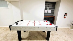 A foosball table in a room with a fireplace and a fire extinguisher on the wall. - Cozy 4BR Retreat | Entire House | King Bed | Airport | Ring Road | Games | Banff (Calgary)