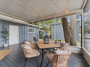 An outdoor covered patio with a wooden table and wicker chairs, a lantern, and a view of the surrounding area. - Modern Gulf Coast Getaway| Near Clearwater and Indian Rocks Beach (Largo)