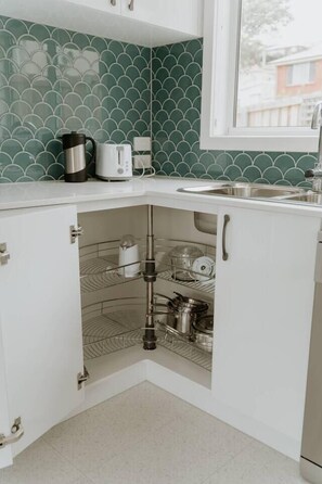 A kitchen with a corner sink, a coffee maker, and a toaster on the countertop. - Cosy central guest house (Bellerive)