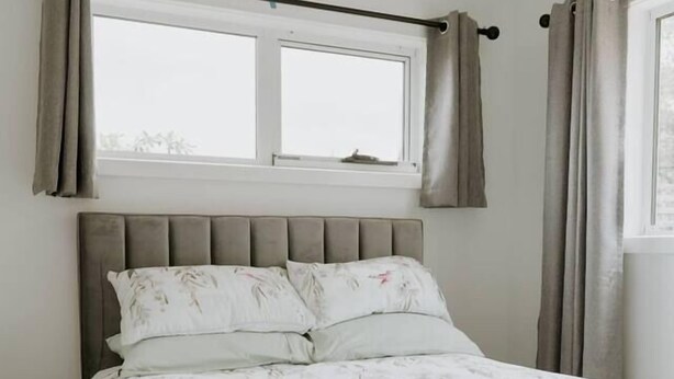 A bed with a headboard, a window with curtains, and a view of the outdoors. - Cosy central guest house (Bellerive)