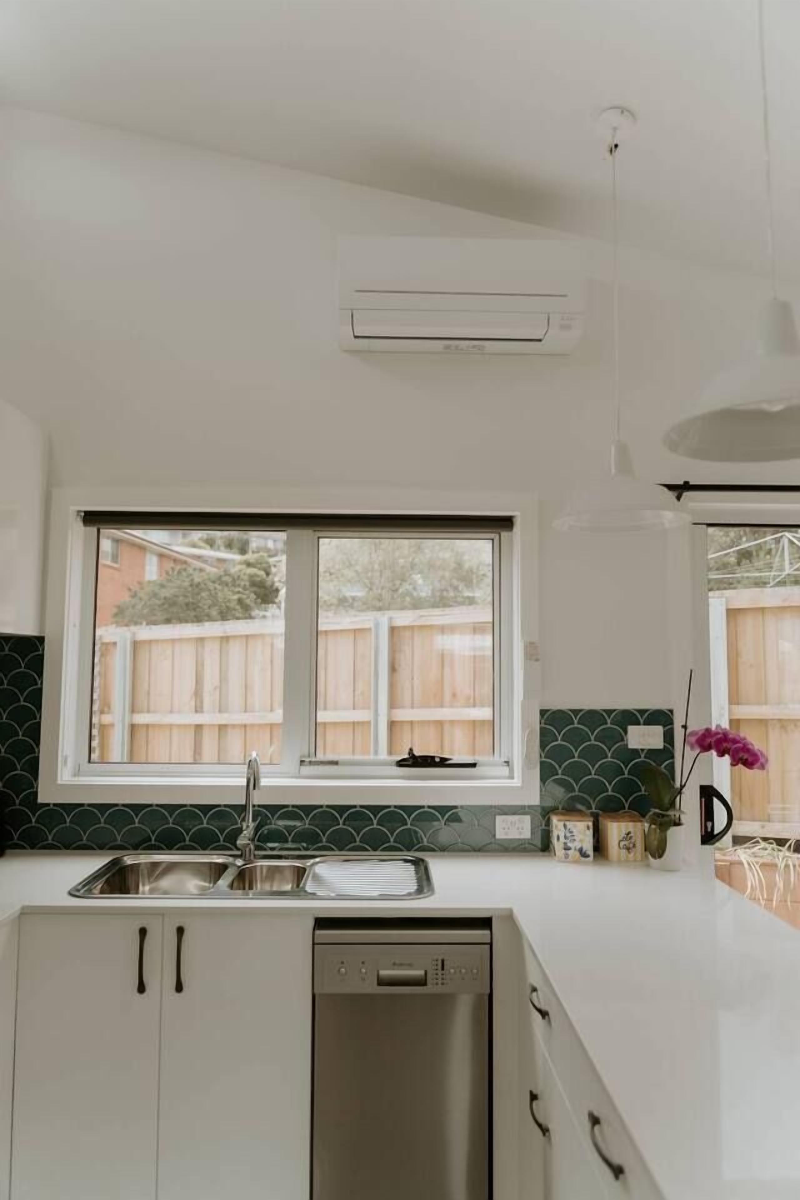 A kitchen with a window, a dishwasher, and a tiled backsplash.