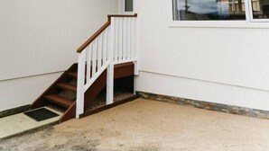 A corner of a building with a white exterior, a wooden staircase, and a large window reflecting the sky. - Cosy central guest house (Bellerive)