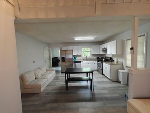 Eine moderne Küche mit weißen Schränken, einem Edelstahl-Kühlschrank und einem Essbereich mit Tisch und Stühlen.
