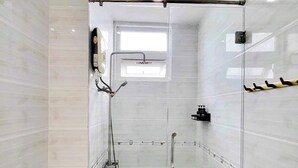 Et moderne badeværelse med en glasbrusekabine, toilet og håndvask.