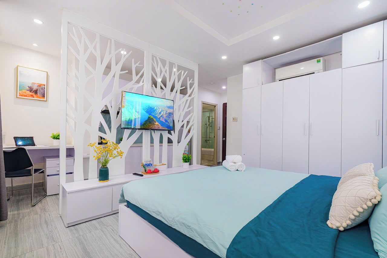 A modern hotel room with a bed, a desk, a TV, and a wardrobe.