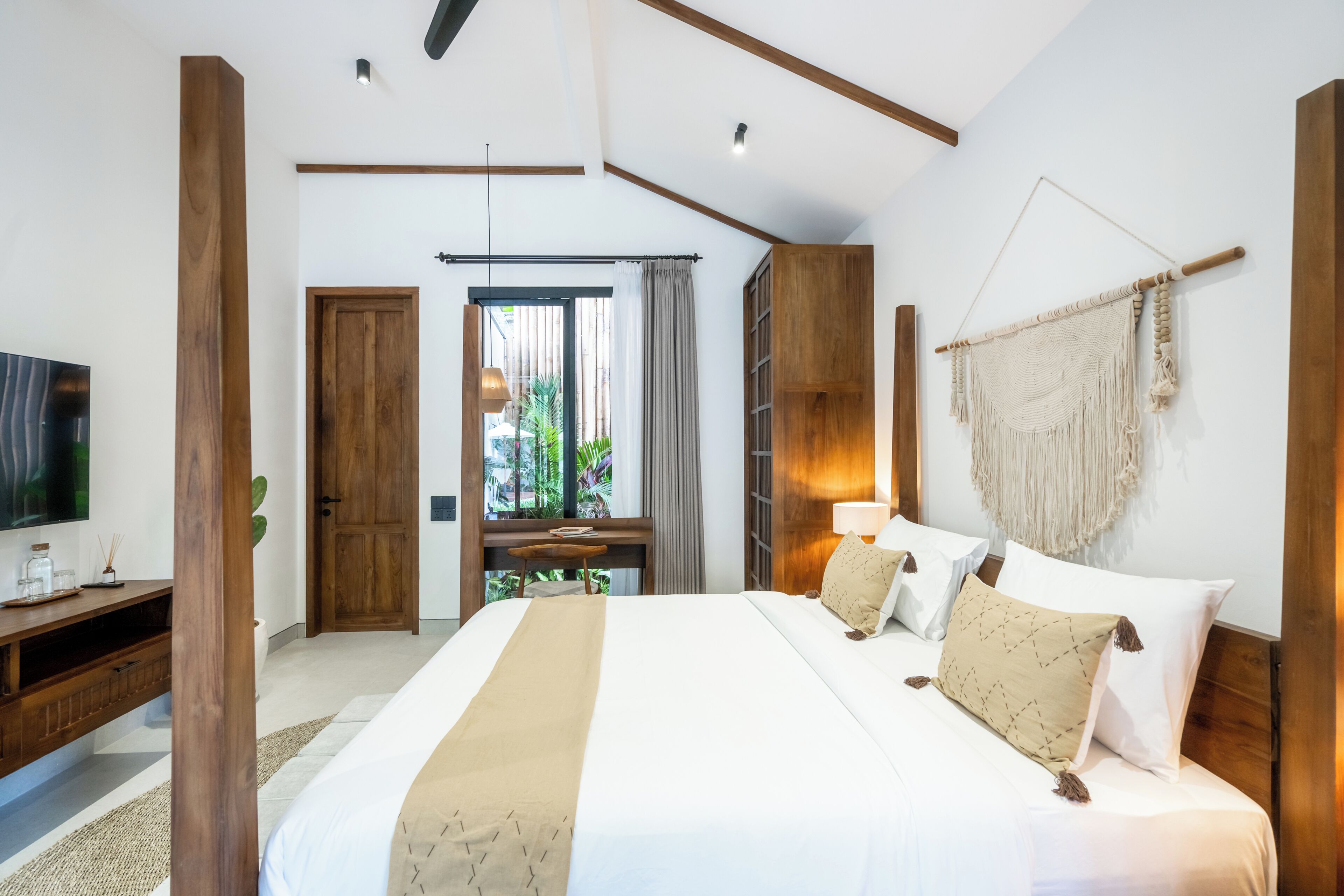 Ein modernes Hotelzimmer mit einem großen Bett, Holzelementen, einem Fernseher und Blick ins Freie.