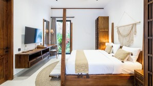Un dormitorio moderno con cama, televisor, muebles de madera y vista a zonas verdes.