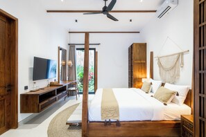 Un dormitorio moderno con cama, televisor, muebles de madera y vista a zonas verdes.