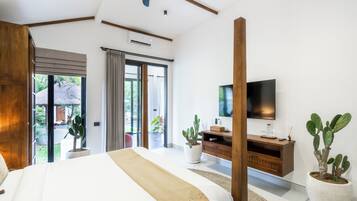 Un dormitorio moderno con una cama grande, un escritorio de madera, un televisor y plantas en macetas.