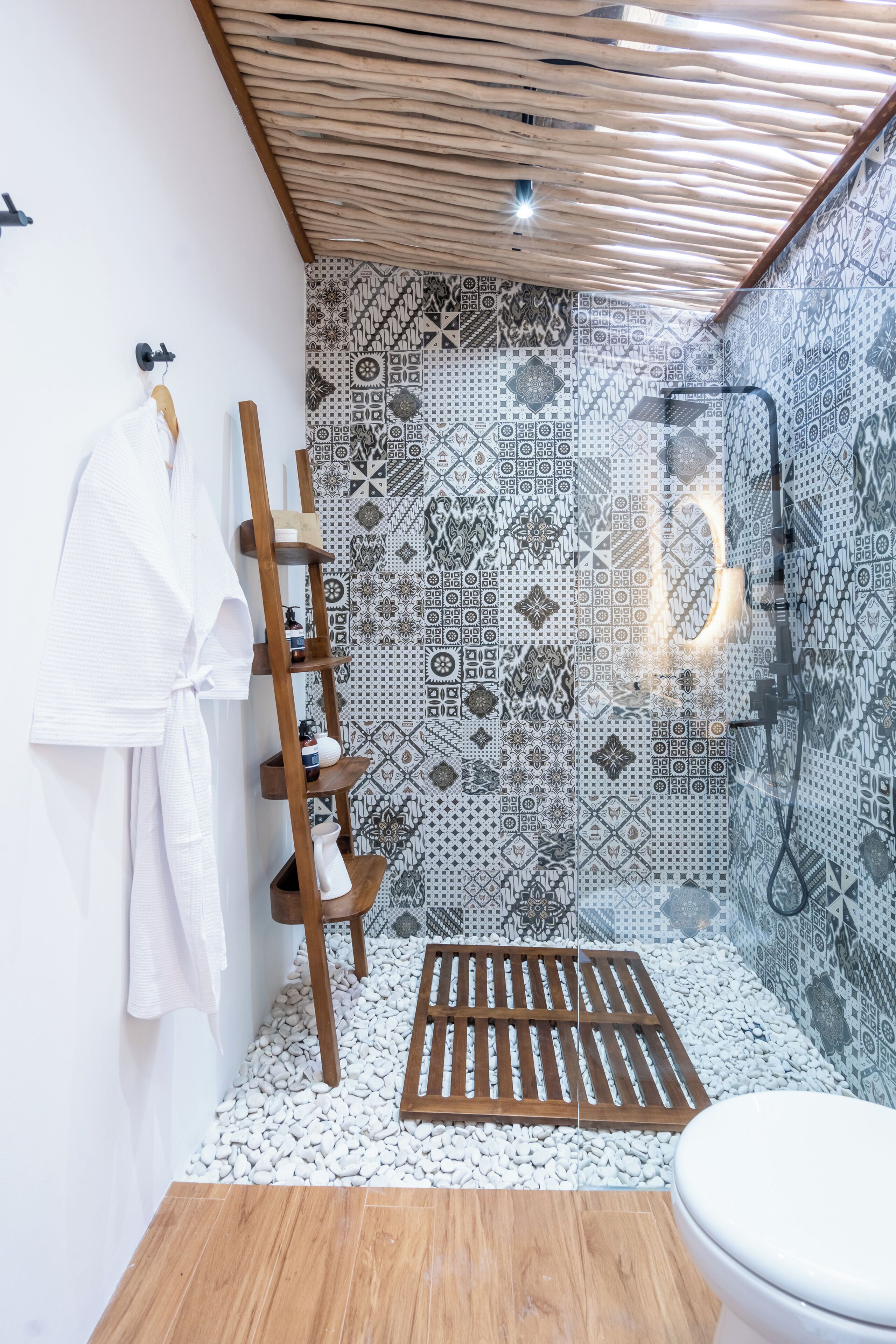 Un baño moderno con ducha, baldosas estampadas, un estante de madera y una bañera blanca.