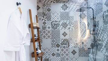 Un baño moderno con ducha, baldosas estampadas, un estante de madera y una bañera blanca.