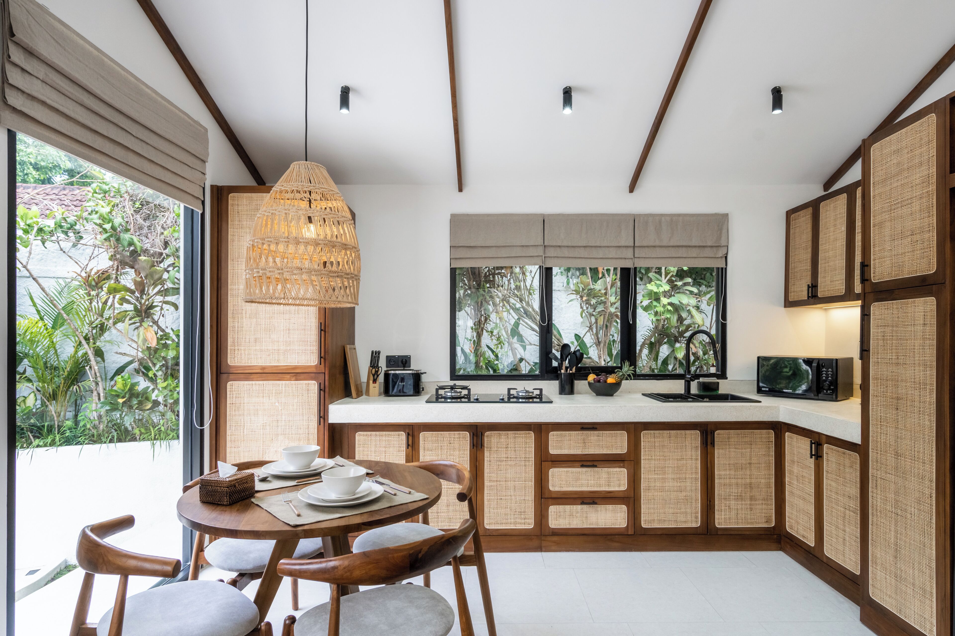 Una cocina moderna con comedor, que cuenta con un amplio ventanal, una lámpara colgante y una estufa integrada.