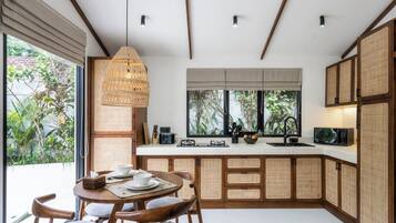 Una cocina moderna con comedor, que cuenta con un amplio ventanal, una lámpara colgante y una estufa integrada.