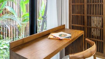 Una habitación con un escritorio de madera, una silla, una lámpara colgante, una cerca de bambú y una puerta corredera.