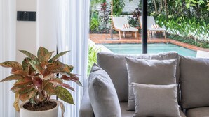 Una sala de estar moderna con un ventanal grande, un sofá gris y una planta en maceta.