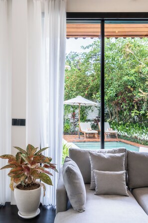 Una sala de estar moderna con un ventanal grande, un sofá gris y una planta en maceta.