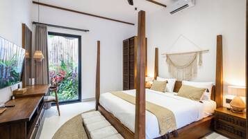 Un dormitorio moderno con una cama grande, cabecera de madera, mesitas de noche, televisión y vistas a la vegetación por la ventana.