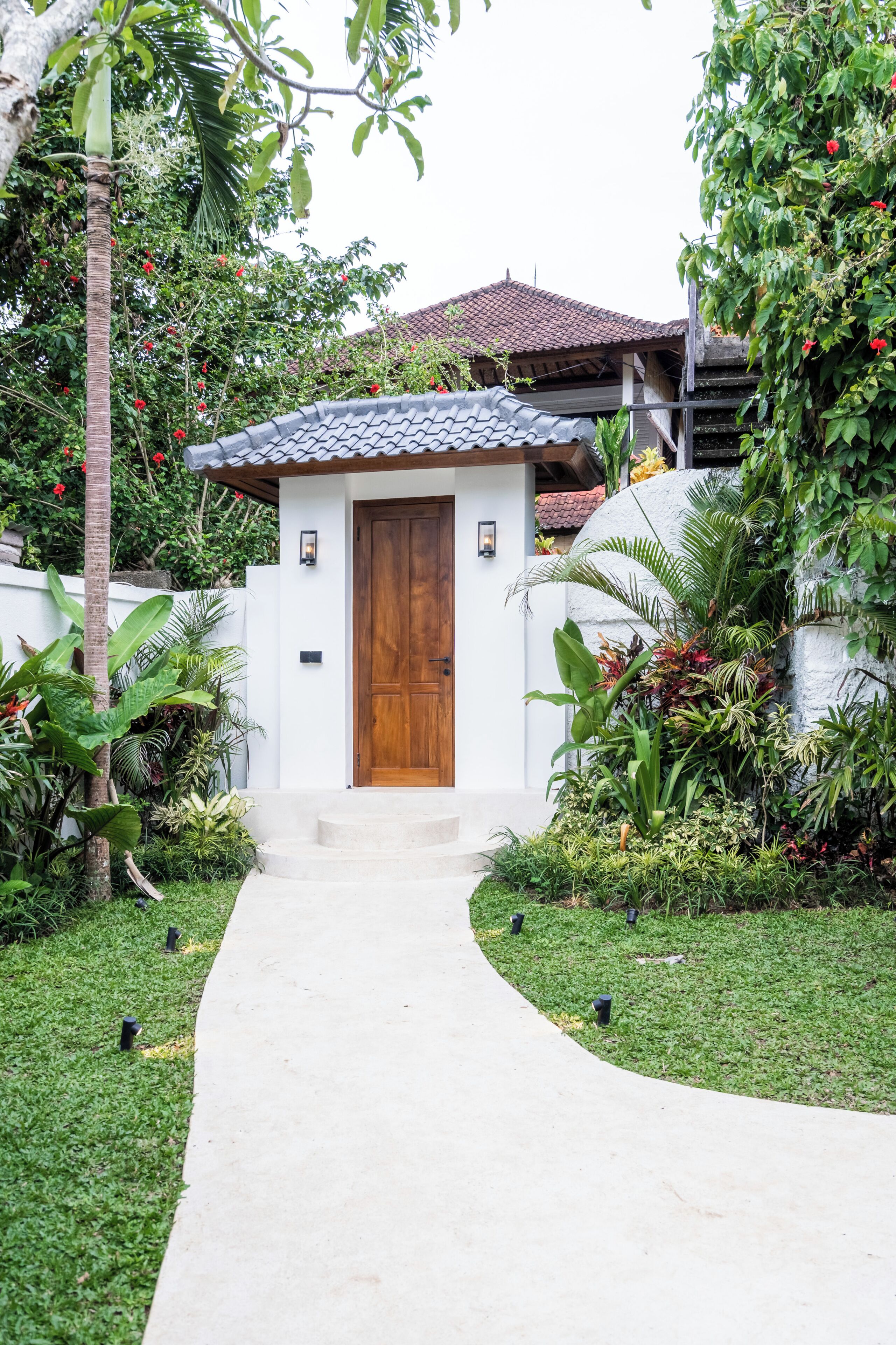 A house with a wooden door, a white exterior, and a tiled roof.