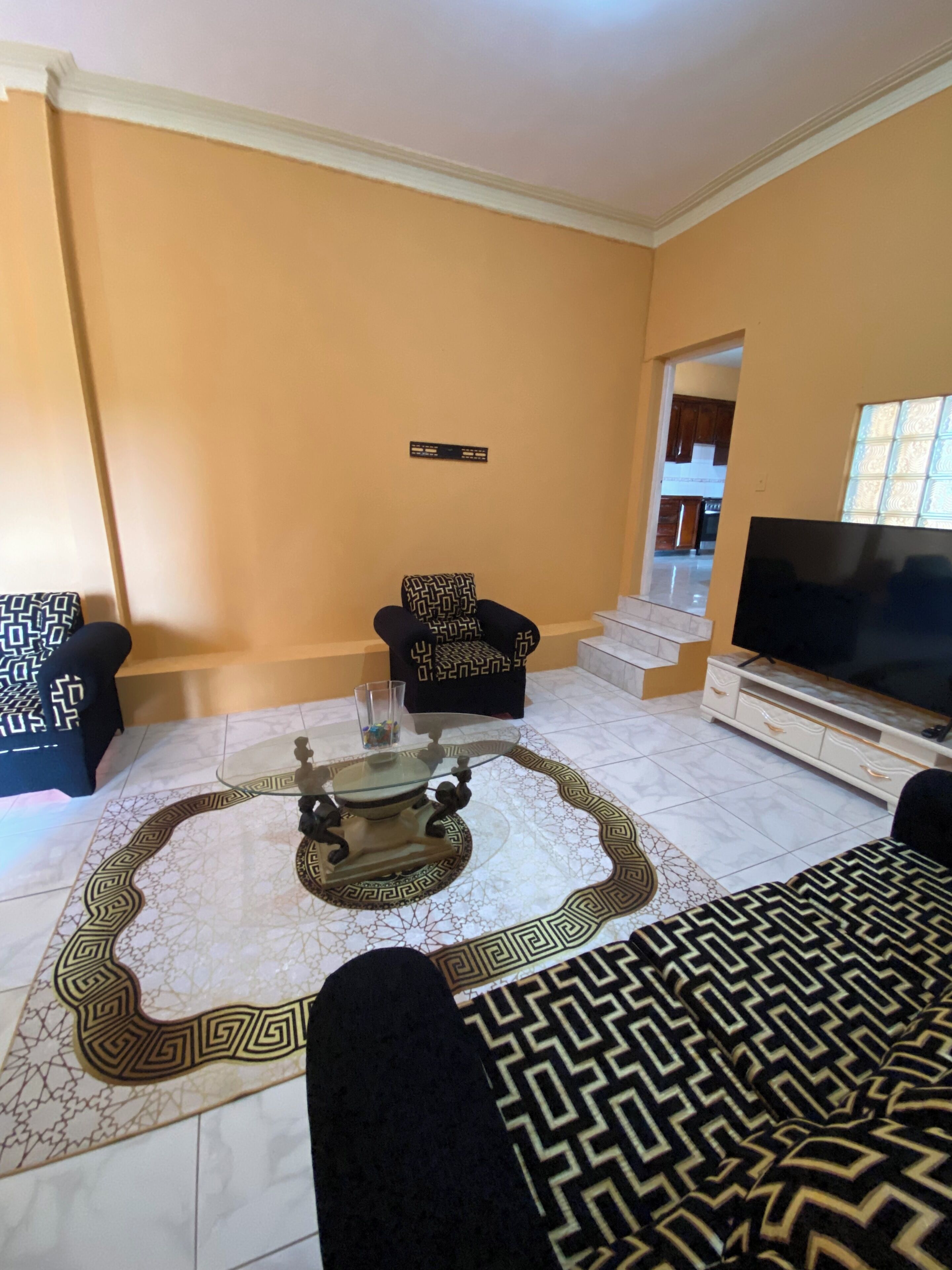 A living room with a sofa, a coffee table, a TV, and a patterned rug.