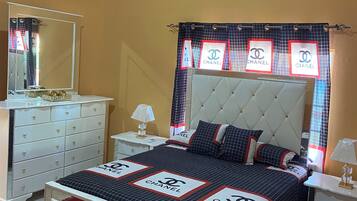 A bedroom with a bed, a dresser, a nightstand, a mirror, and a window with a curtain.