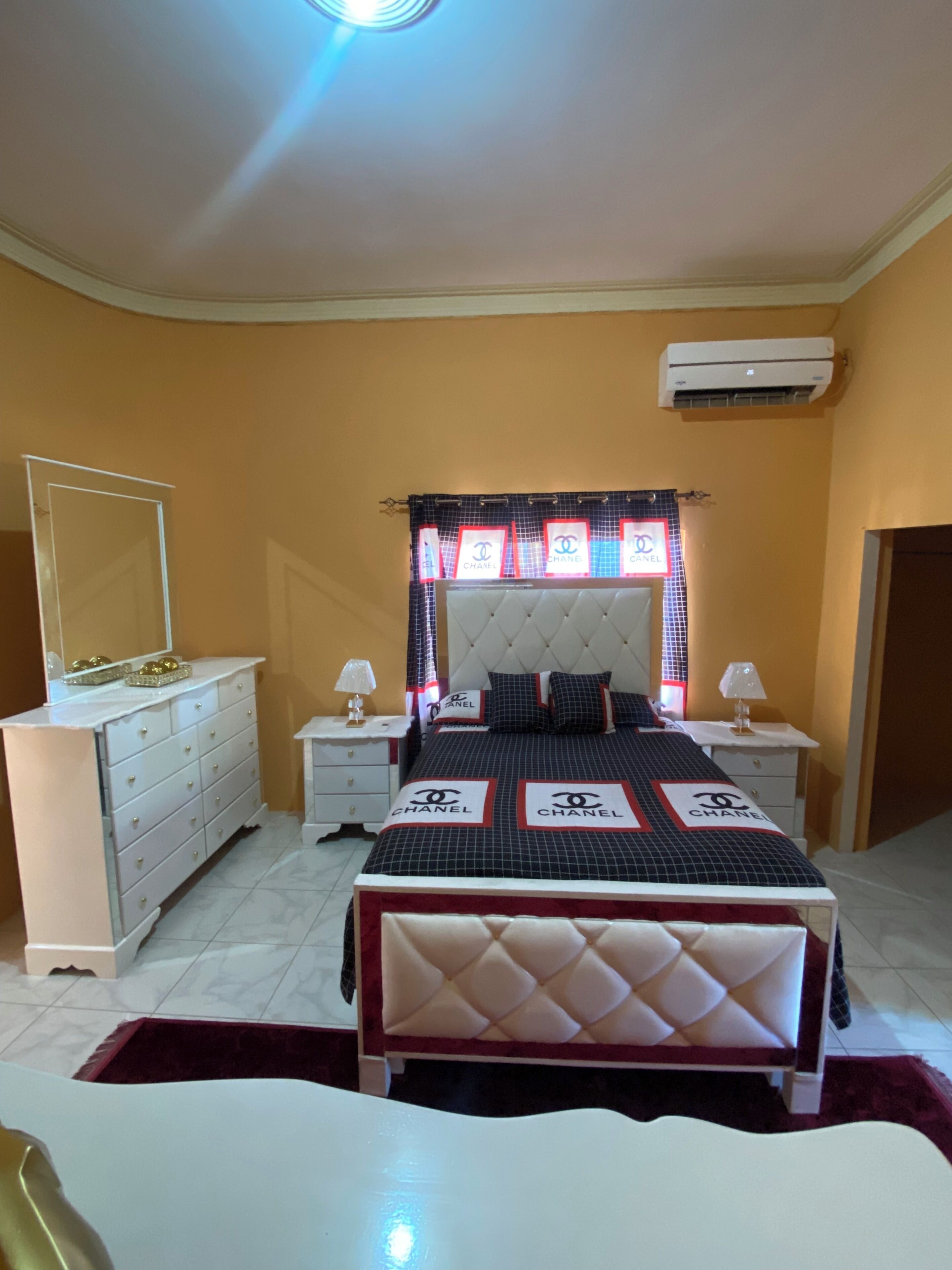 A bedroom with a bed, nightstands, a dresser, a mirror, and a window with a curtain.