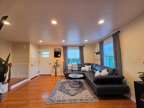 A modern living room with a black leather sofa, a patterned rug, and a small round coffee table. - Luxury Cozy Stay-Near Six Flags, Navy Base (Gurnee)