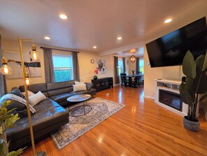 A modern living room with a sofa, coffee table, and TV. - Luxury Cozy Stay-Near Six Flags, Navy Base (Gurnee)