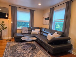 A modern living room with a sectional sofa, a round coffee table, and a patterned rug. - Luxury Cozy Stay-Near Six Flags, Navy Base (Gurnee)