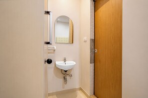Un baño con un lavamanos blanco, un espejo y una puerta de madera.