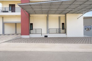 A building with a covered entrance, a red pillar, and a sign that reads 'RESEPSIONIS'.