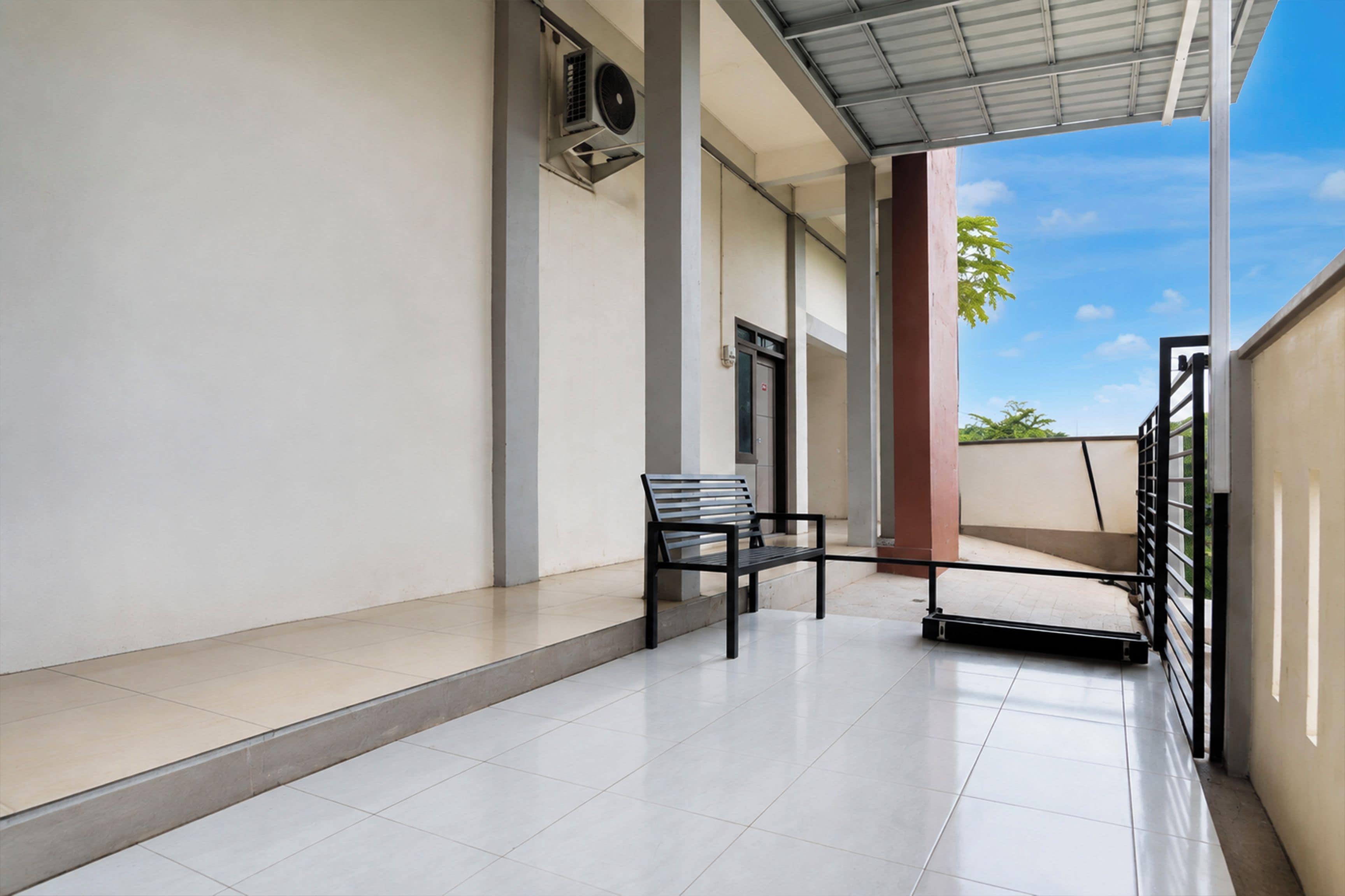 A clean, modern outdoor area with a bench, a door, and a view of the sky.