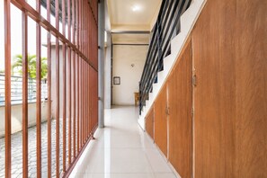 A corridor with a tiled floor, metal railings, and wooden cabinets.