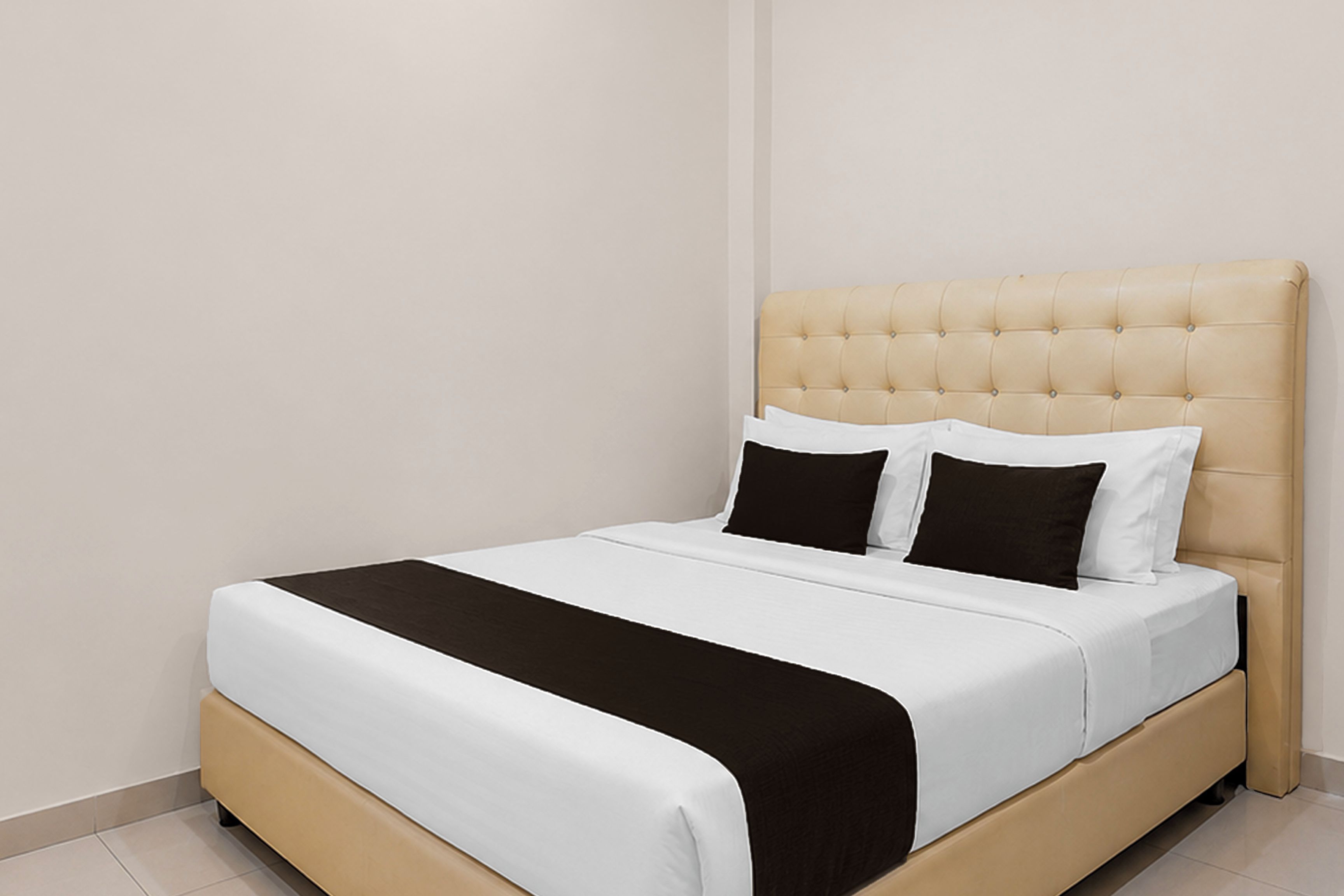 A bed with a tufted headboard, white bedding, and two black pillows.
